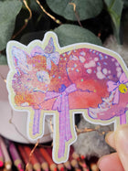 Close-up of Wander Fawn holographic sticker showing glitter shimmer and hand-drawn ribbon detail