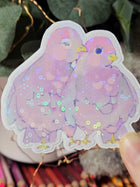 Close-up of Wander Pigeons holographic sticker showing glitter shimmer and hand-drawn feather detail