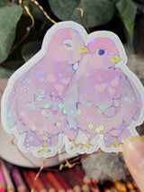 Close-up of Wander Pigeons holographic sticker showing glitter shimmer and hand-drawn feather detail