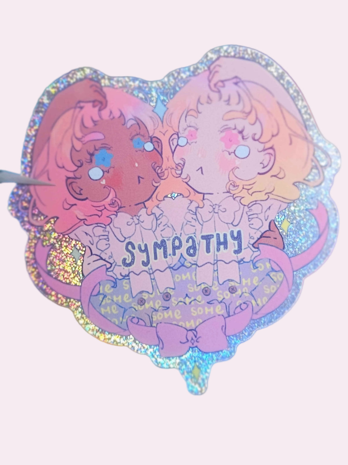 Some Sympathy holographic glitter die-cut sticker — two figures of different skin tones facing each other with arms reaching to form a heart, the word "some" repeated as a pattern across their skirts, original Signature Collection artwork by Ailyse of Finding Wonderland